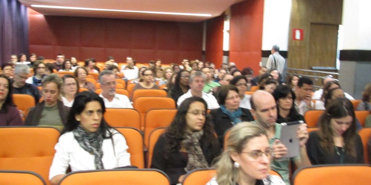 Audience seated in an auditorium, some focused and attentive.