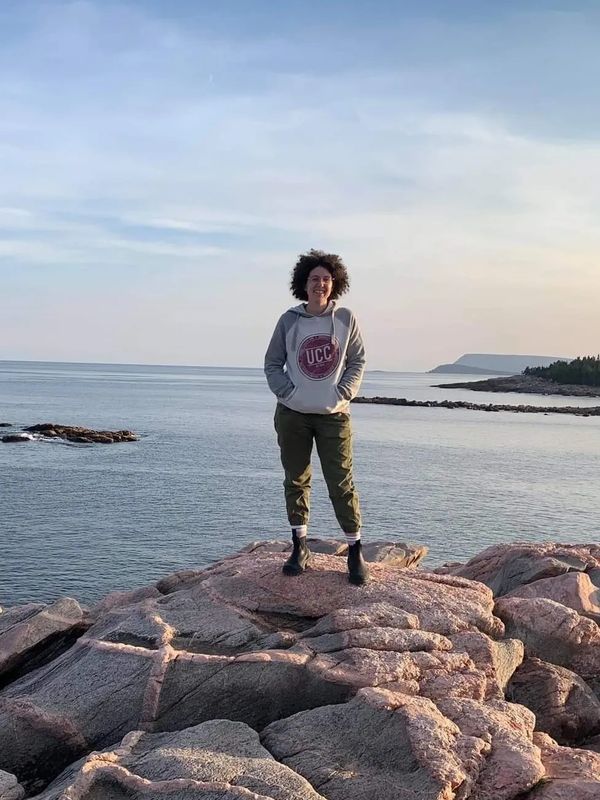 Lisa stands on rocks by the ocean in Nova Scotia.