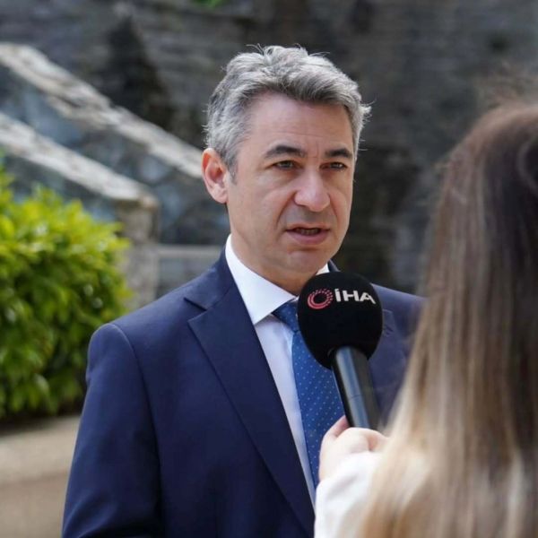 Man in suit being interviewed outdoors with a microphone labeled İHA.