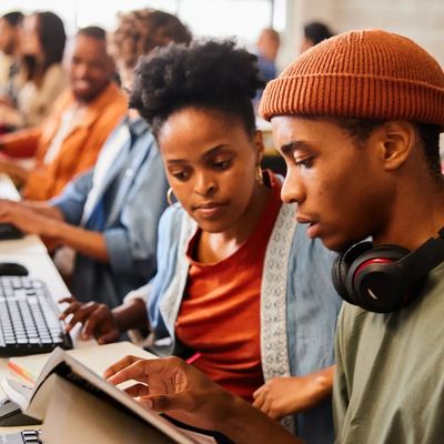Two young adults studying together with books and computers.
