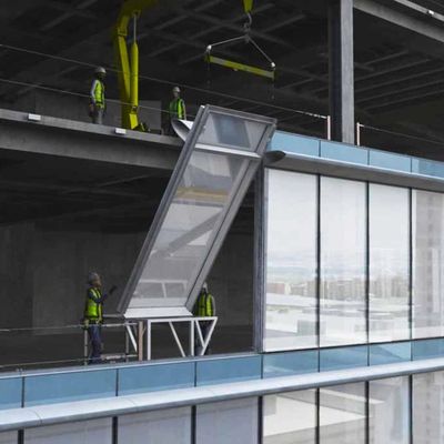 Workers installing a large glass panel on a building.