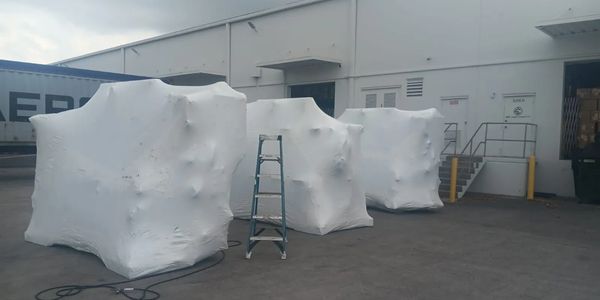 Three large objects wrapped in white material outdoors.