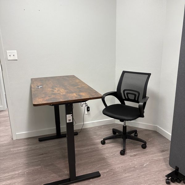 Minimalist office corner with a wooden desk and ergonomic black chair.