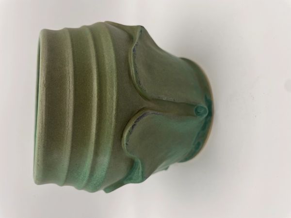 Green ceramic pot with a unique textured design and a matte finish.