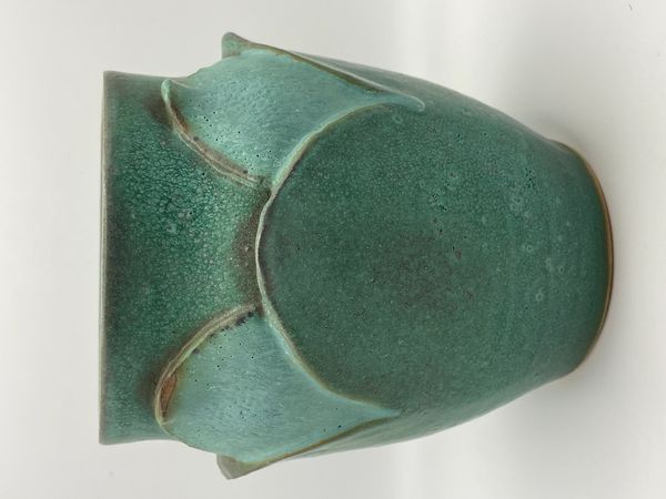 Green ceramic vase with textured glaze and petal-like designs on the sides.