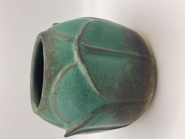 A small, green ceramic vase with textured, leaf-like patterns.