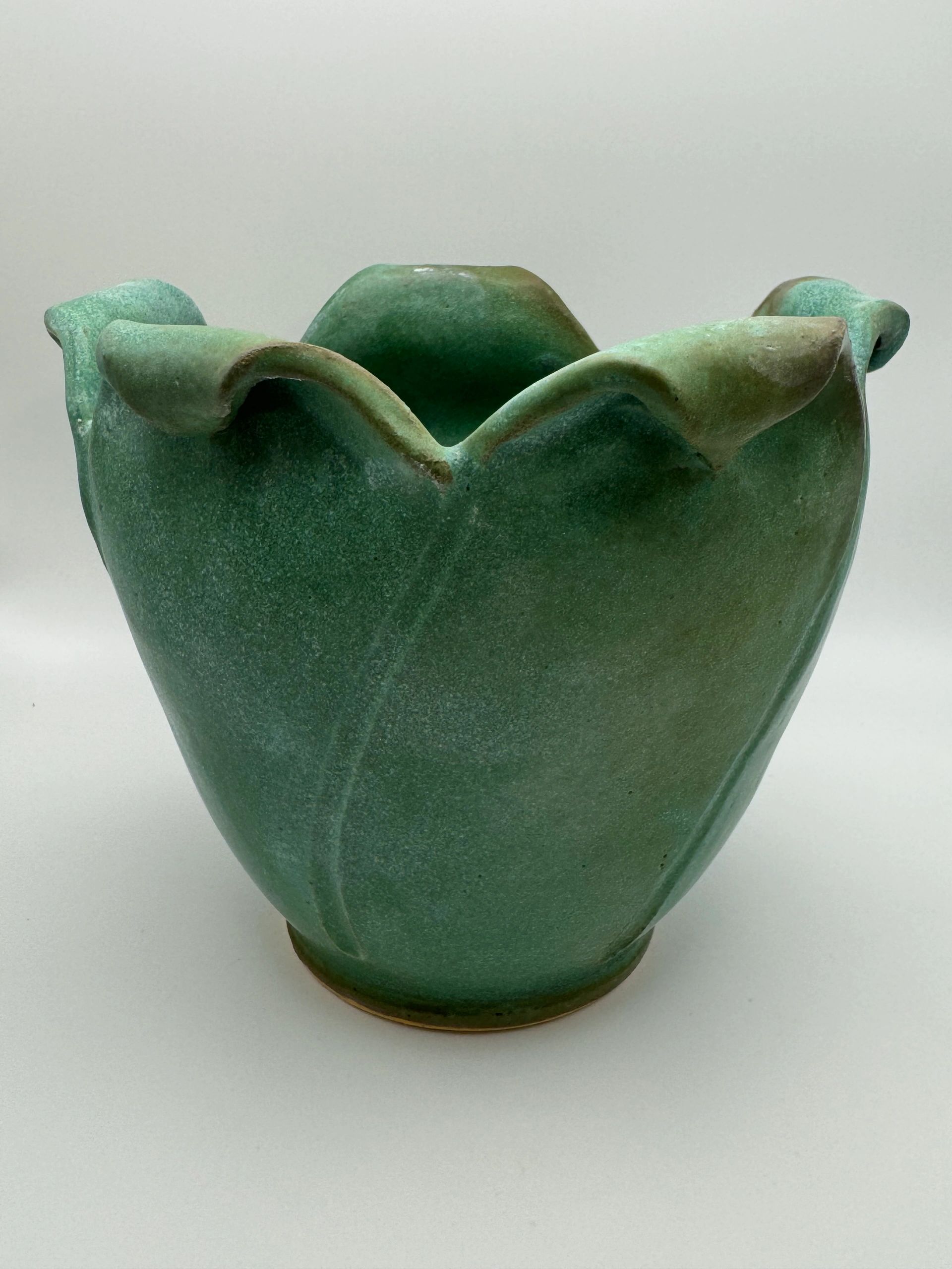 Green ceramic vase with petal-like edges.