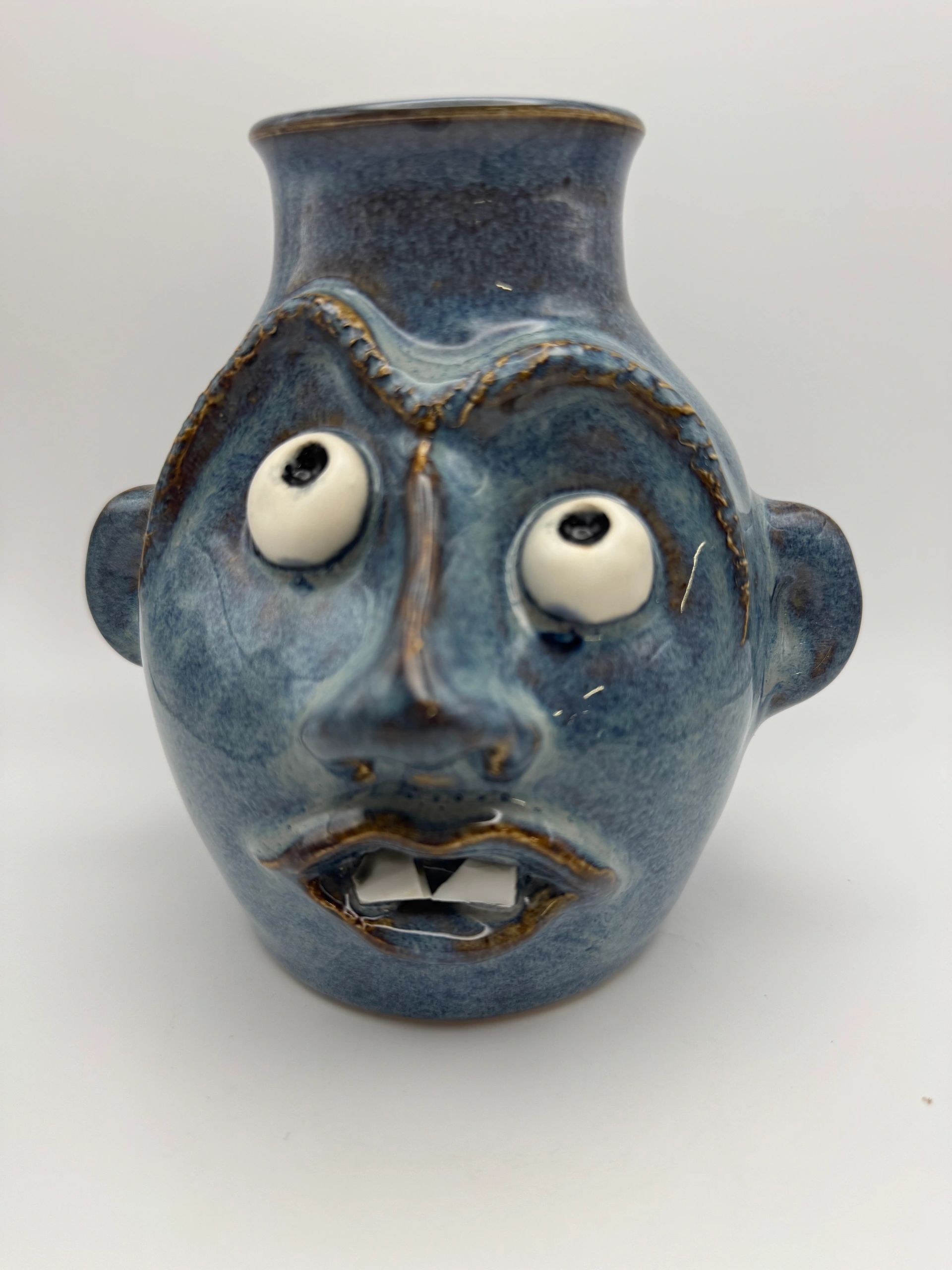 Blue ceramic vase with a quirky face design.