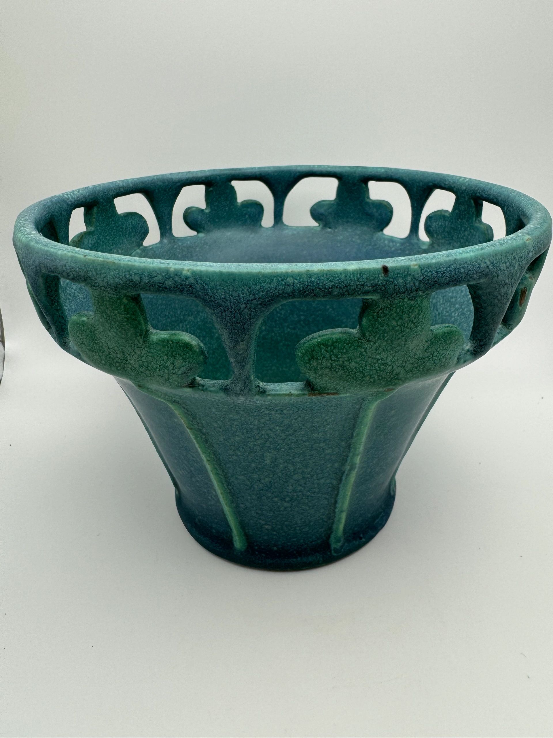Blue-green ceramic vase with intricate cut-out patterns.