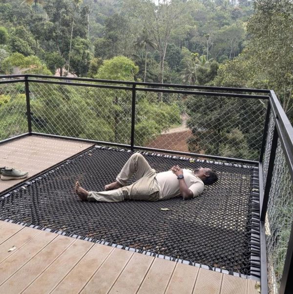 Man relaxing on a hammock net on a balcony.