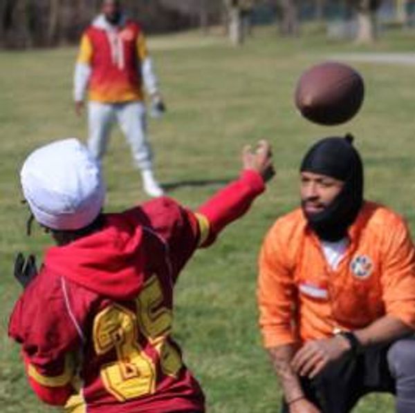 Young men playing football in a park, one throwing the ball to another.