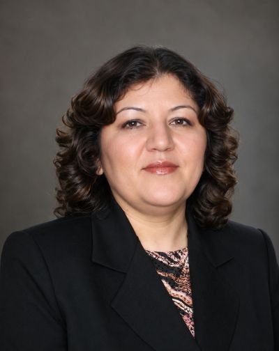 Professional portrait of a woman with curly hair in a black blazer.