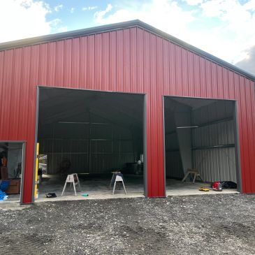 Large red metal garage with two open bays.