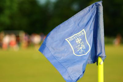 Blue corner flag with Heather emblem on a soccer field.