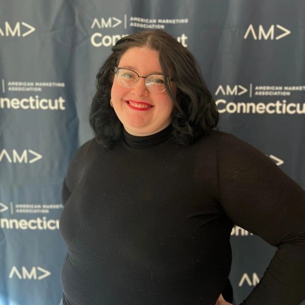 Kyra Bernor  in front of American Marketing Association Connecticut Chapter backdrop.