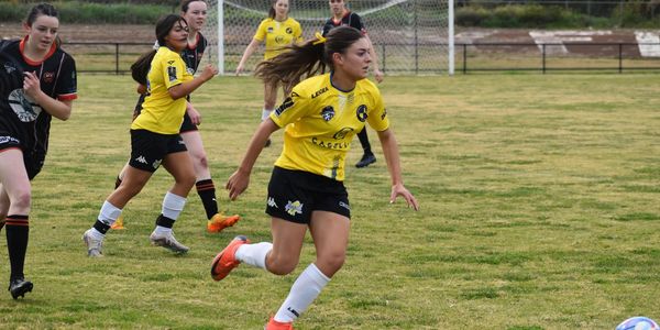 Female soccer players in action on a grass field during a match.