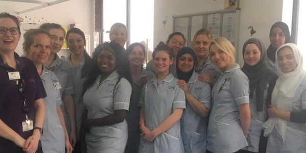 Photo of Liz King with some nursing students in a mock children's ward in a university 