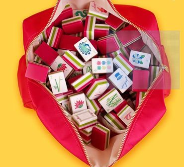 Mahjong tiles spilling from a red pouch on a yellow background.
