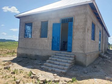 Newly built concrete house with blue doors and windows in a rural area.