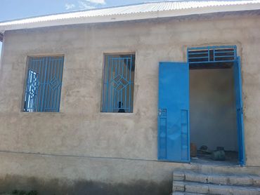 Simple building with blue metal windows and door under a clear sky.