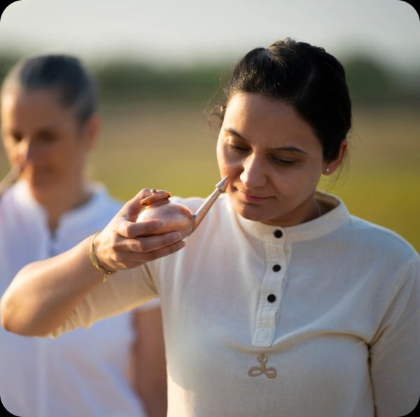 Woman using a neti pot for nasal cleansing outdoors.