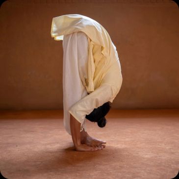 Person in yellow outfit performing a deep forward bend yoga pose indoors.