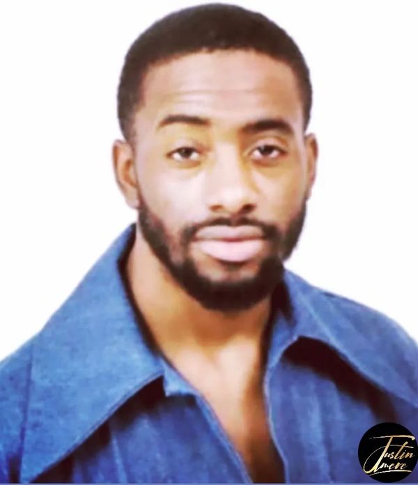 Man with a beard wearing a blue shirt against a white background.