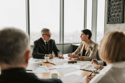 A group of professionals engaged in a meeting around a table with documents and coffee.
