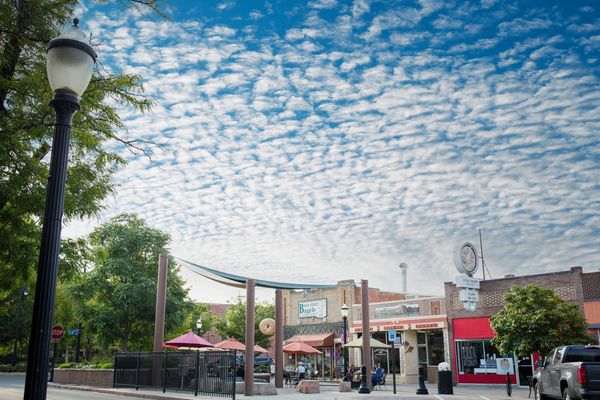 Outdoor dining area under a sky filled with scattered clouds in a small town.