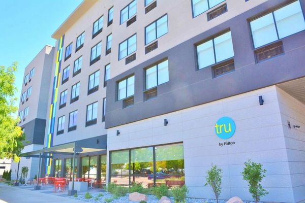 Exterior view of a modern Tru by Hilton hotel with outdoor seating.