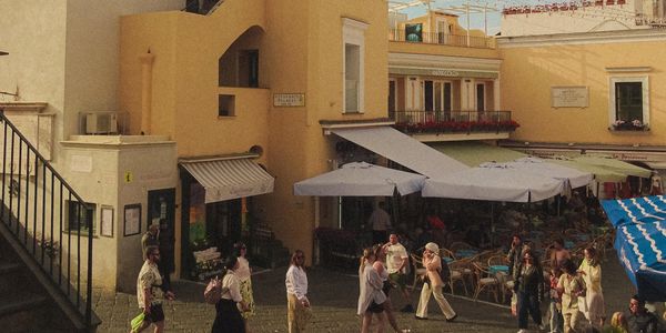 Persone che passeggiano vicino a un edificio giallo con caffè all'aperto.