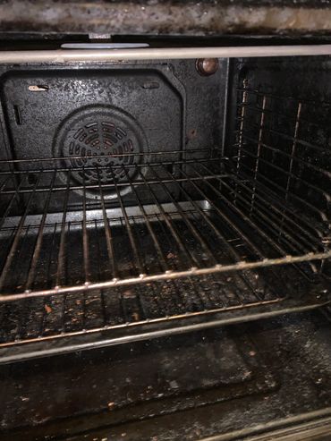 Dirty oven interior with food debris on racks and bottom.