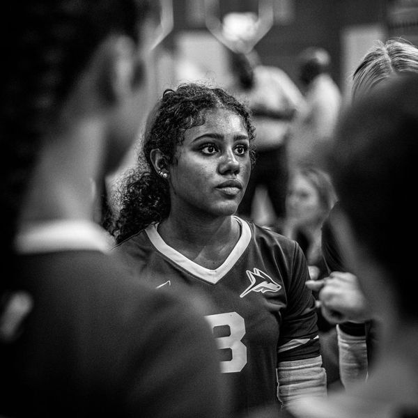 Focused female volleyball player in jersey number 3 during a team huddle.