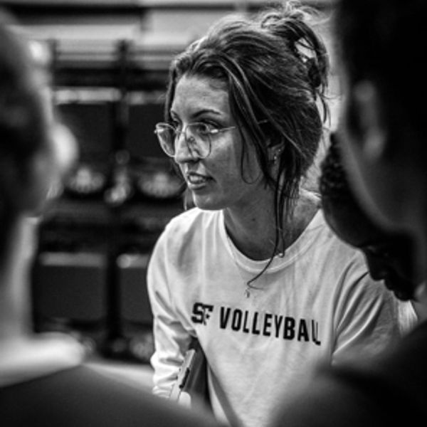 Woman in a volleyball shirt speaking during a group discussion.
