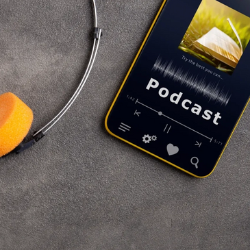Orange headphones and a phone playing a podcast on a gray surface.