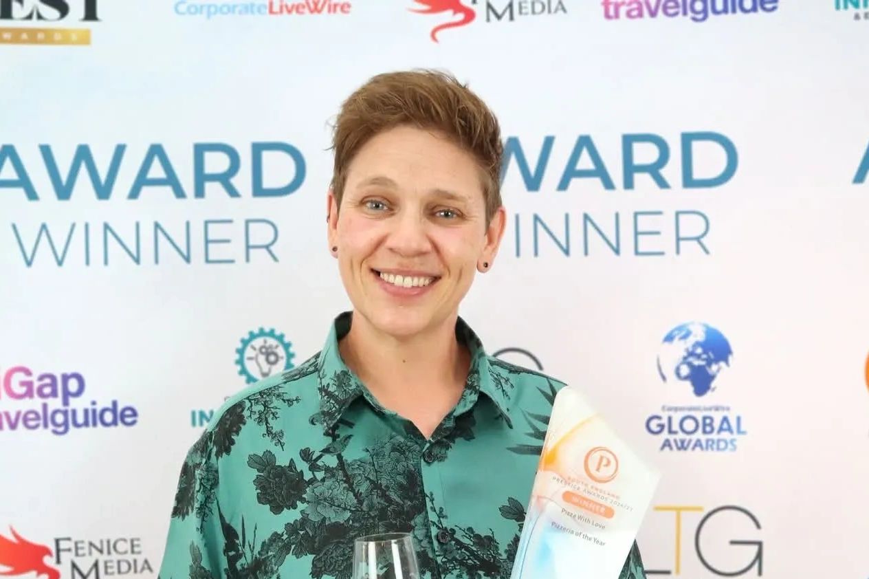 Person smiling holding an award and glass.