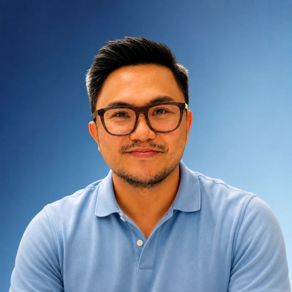 Man with glasses and blue polo shirt smiling.