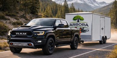 Black RAM truck towing an Arbora trailer on a mountain road.