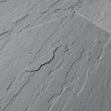 Close-up of textured gray stone surface with natural cracks and lines.