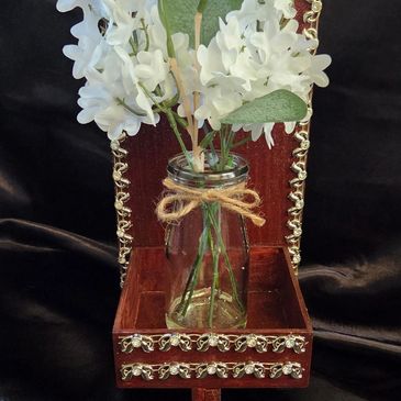 White flowers in a decorated glass jar with twine bow.