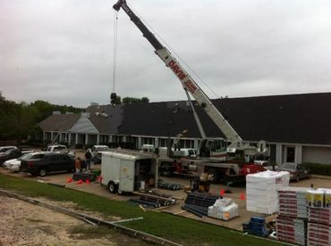 Crane lifting materials for roof repairs at a residential building.