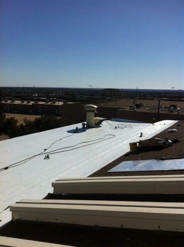 A flat white roof with ventilation pipes under a clear blue sky.