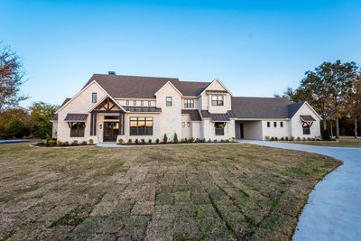 Large modern farmhouse with light stone exterior.