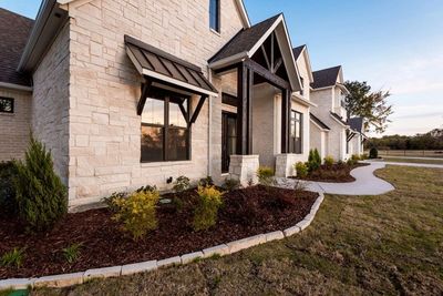 White stone farmhouse exterior with black window awnings.