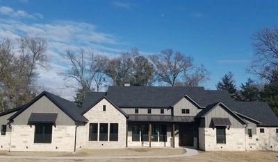 Modern farmhouse with white stone and gray siding exterior.