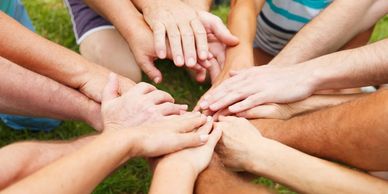 Multiple hands joined together in a circle symbolizing unity.