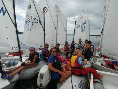 Group of young sailors gathered on boats preparing to sail.