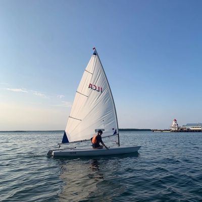 A person sailing a small boat on calm water under a clear sky.