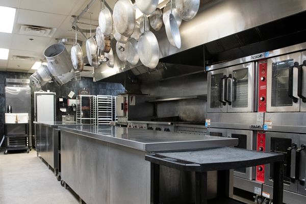 Professional commercial kitchen with stainless steel appliances and hanging pots.