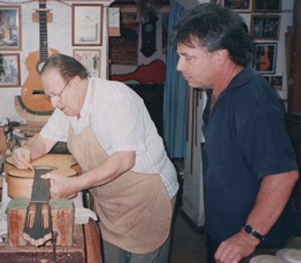 A person watching someone fixing a guitar